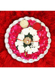 Decorative plate with flowers, jewelry, and red powder on a red textured background